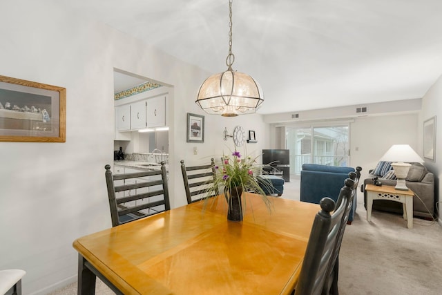 dining room featuring a notable chandelier, light colored carpet, and visible vents