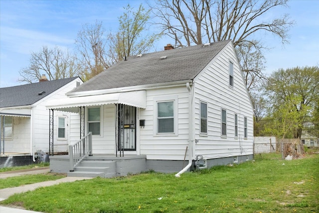 view of front facade featuring fence, a chimney, roof with shingles, and a front lawn