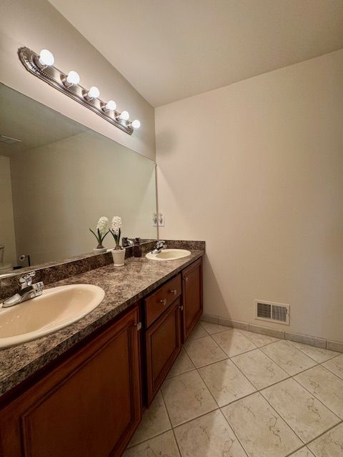 bathroom with double vanity, a sink, tile patterned floors, and visible vents