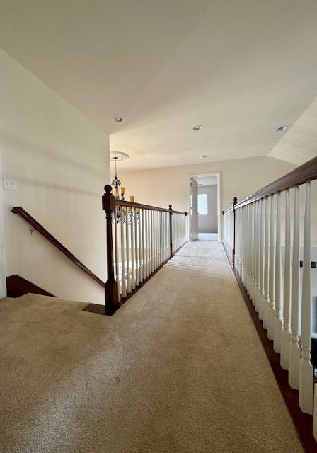 hall with lofted ceiling and dark colored carpet