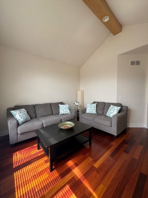 living room featuring baseboards, visible vents, wood finished floors, and lofted ceiling with beams