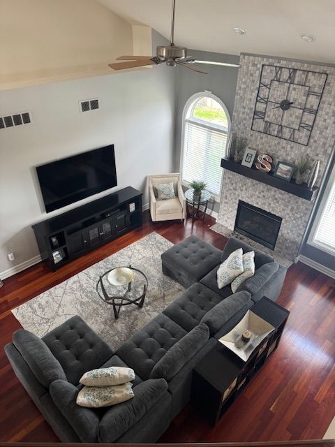 living area featuring a fireplace, visible vents, a ceiling fan, and baseboards