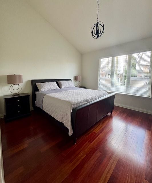 bedroom with baseboards, wood finished floors, and vaulted ceiling