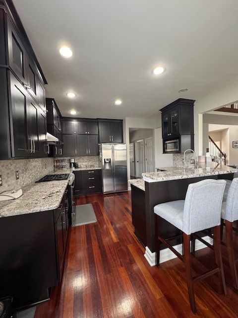 kitchen featuring light stone countertops, a peninsula, appliances with stainless steel finishes, and dark wood-type flooring