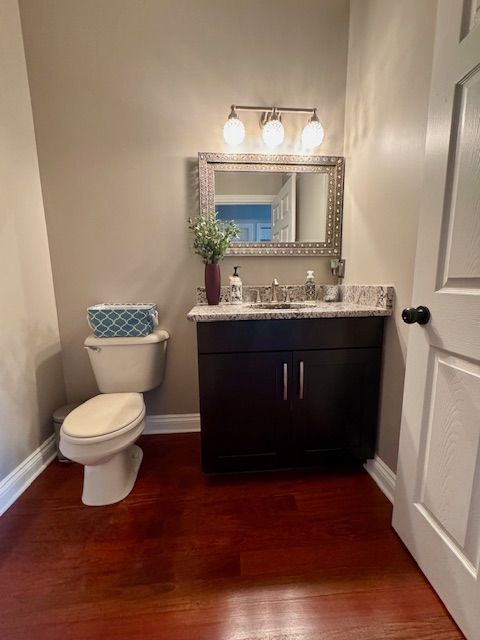 bathroom featuring wood finished floors, toilet, vanity, and baseboards