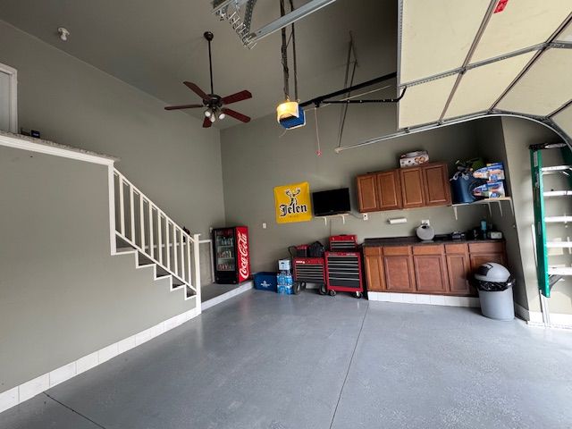 garage with a garage door opener, a ceiling fan, and baseboards