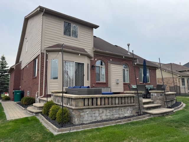rear view of house with brick siding, fence, a patio area, and a lawn