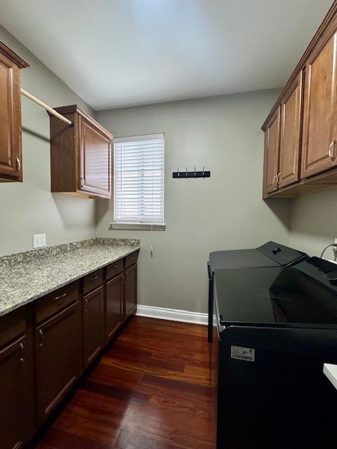 laundry room featuring baseboards, washer and clothes dryer, cabinet space, and dark wood-style flooring