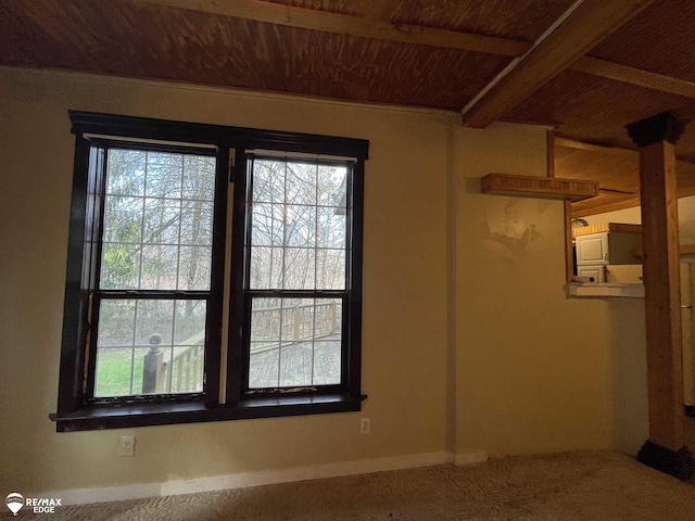 carpeted empty room with beam ceiling, baseboards, and wooden ceiling