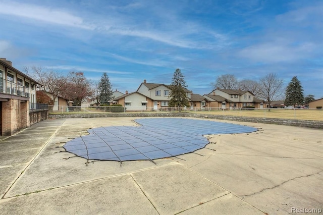 community pool with fence, a patio area, and a residential view