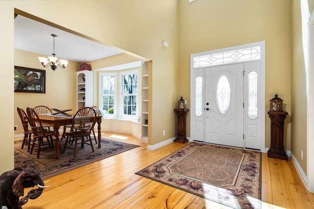 entryway with a high ceiling, a notable chandelier, baseboards, and wood-type flooring