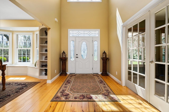 foyer entrance featuring a towering ceiling, hardwood / wood-style floors, and baseboards