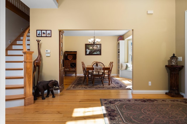 dining room with stairway, wood finished floors, a chandelier, and baseboards