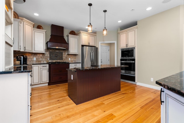 kitchen featuring oven, premium range hood, freestanding refrigerator, and backsplash