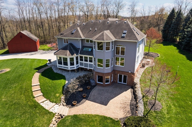 back of property with an outbuilding, a lawn, a garage, and roof with shingles
