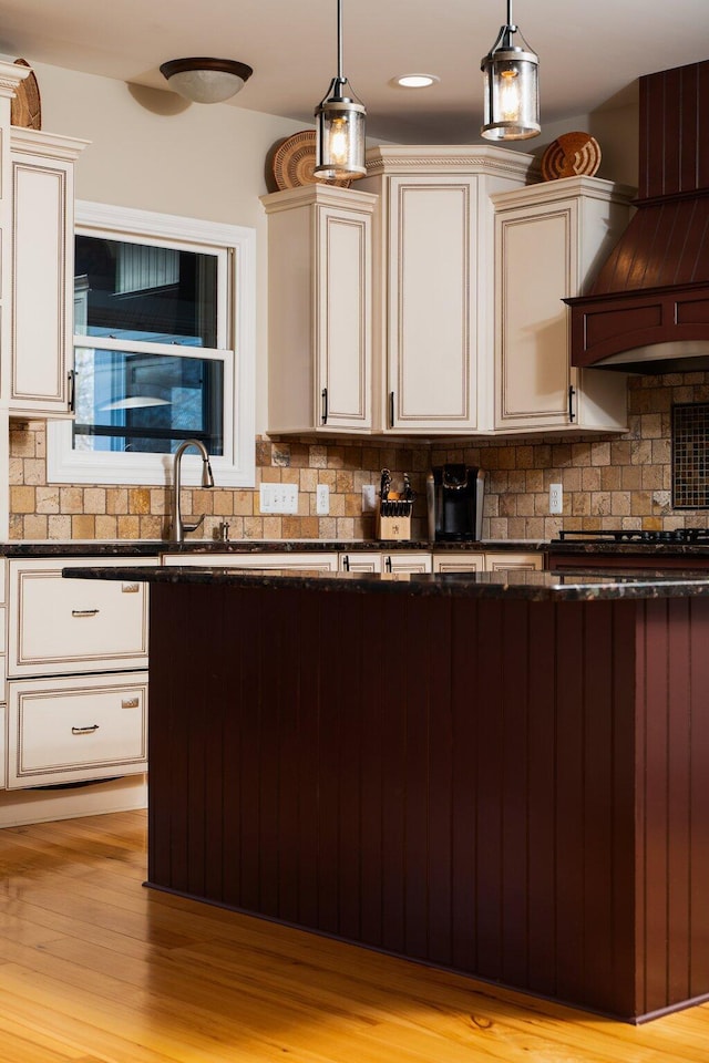 kitchen with tasteful backsplash, pendant lighting, gas cooktop, and light wood finished floors