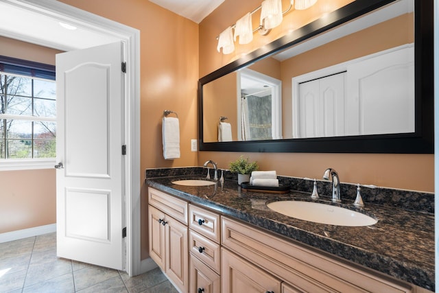 full bath with double vanity, a sink, tile patterned floors, and baseboards
