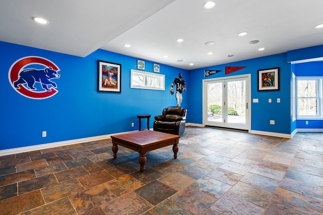 sitting room featuring recessed lighting, stone tile floors, a wealth of natural light, and baseboards
