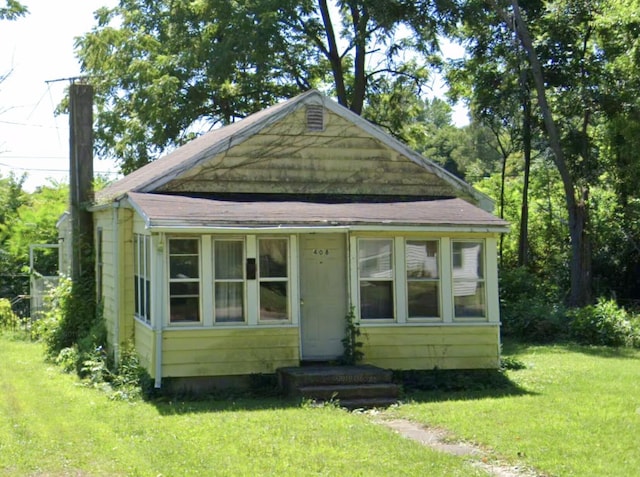 view of front of home featuring a front yard and a shingled roof