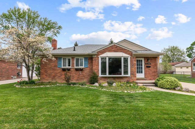 view of front of home featuring brick siding, a front lawn, fence, and a chimney