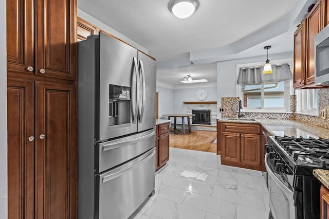 kitchen with decorative backsplash, marble finish floor, a glass covered fireplace, a sink, and appliances with stainless steel finishes