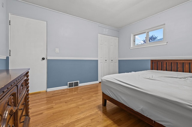 bedroom with a closet, baseboards, visible vents, and light wood-style floors