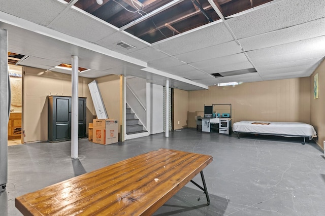 finished basement with a drop ceiling, stairs, and visible vents