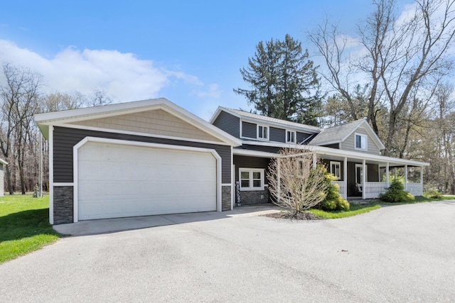 view of front of house featuring a garage, concrete driveway, a porch, and stone siding