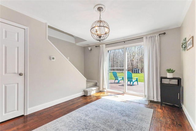 interior space with a chandelier, baseboards, ornamental molding, wood finished floors, and stairs