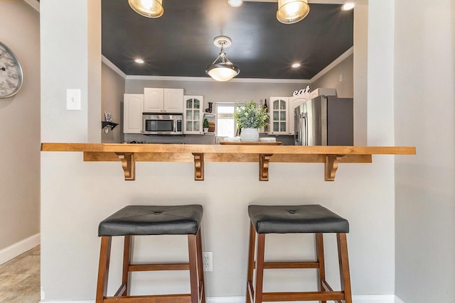 kitchen featuring white cabinetry, stainless steel appliances, a breakfast bar, and crown molding