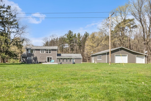 rear view of house with a detached garage, an outbuilding, and a lawn