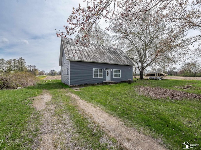 view of home's exterior featuring a lawn, metal roof, and dirt driveway