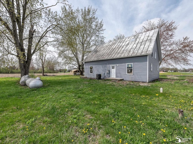 exterior space with cooling unit, metal roof, and a yard