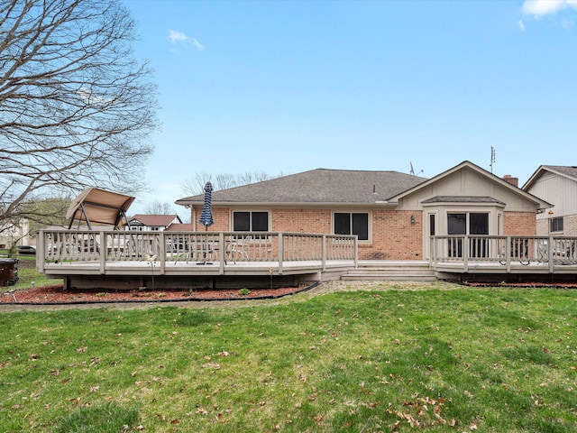 rear view of house with brick siding, a wooden deck, and a yard