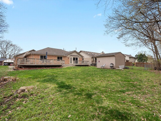 rear view of house featuring a lawn, a deck, and fence