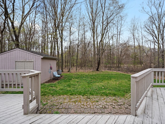 wooden terrace featuring a lawn and an outbuilding