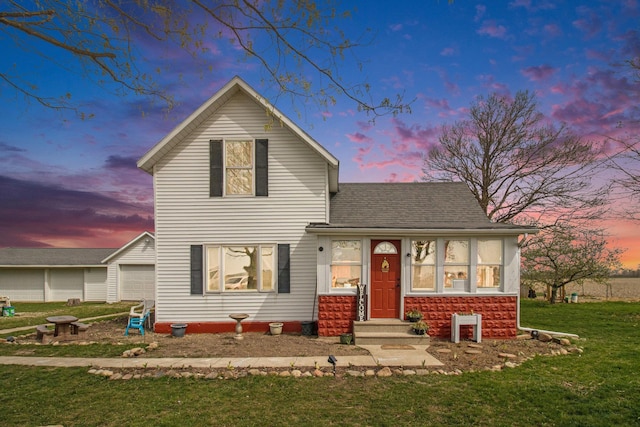 traditional-style house with a shingled roof, a front lawn, and a garage