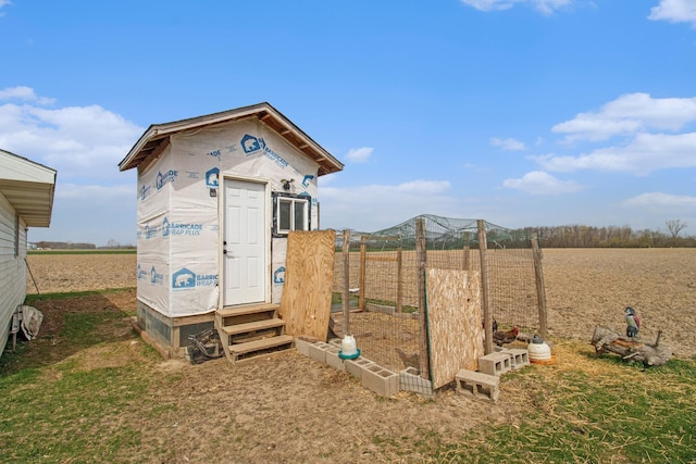 view of outbuilding with a rural view, entry steps, and fence