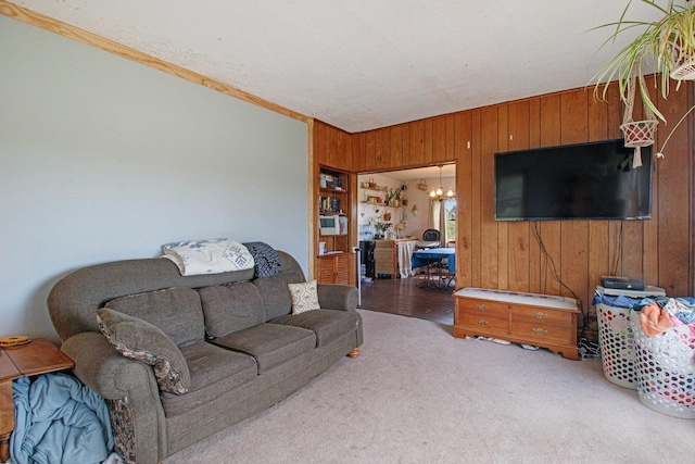 living room with wood walls, an inviting chandelier, and carpet floors