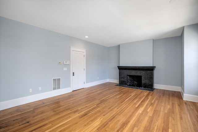 unfurnished living room featuring visible vents, baseboards, recessed lighting, a tiled fireplace, and light wood finished floors