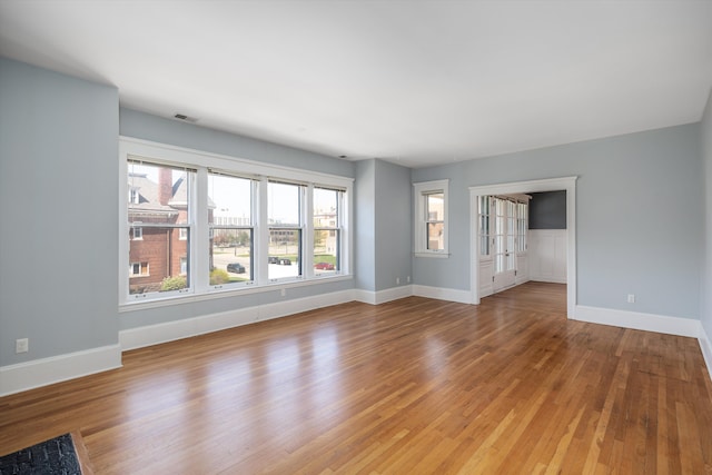 unfurnished living room with baseboards, visible vents, and light wood-type flooring