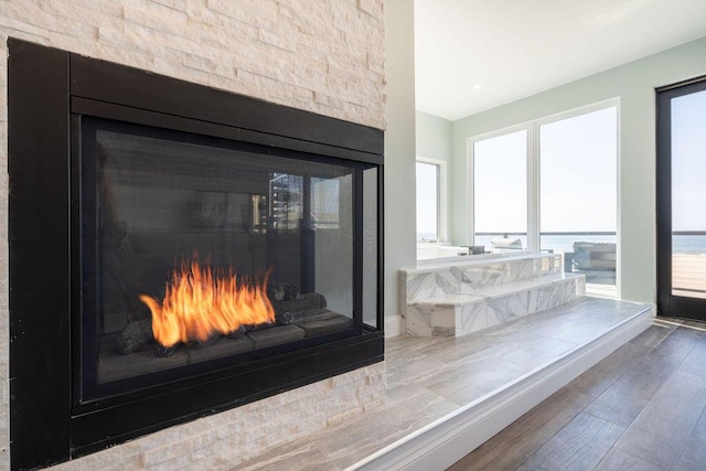 room details with a warm lit fireplace and wood finished floors