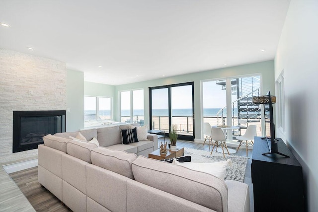 living room with recessed lighting, a stone fireplace, and wood finished floors