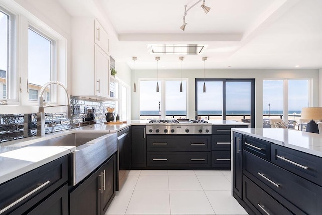 kitchen with appliances with stainless steel finishes, a sink, white cabinetry, a peninsula, and pendant lighting
