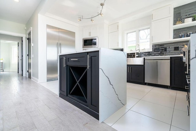 kitchen featuring built in appliances, white cabinetry, open shelves, and a sink