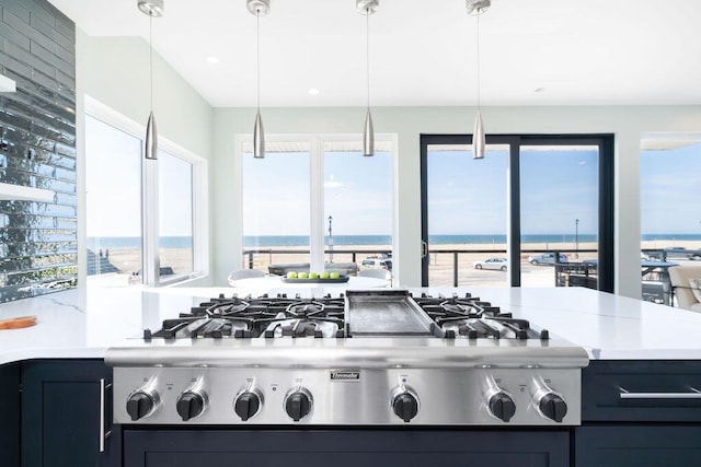 kitchen with light countertops, a water view, stainless steel gas cooktop, and a healthy amount of sunlight