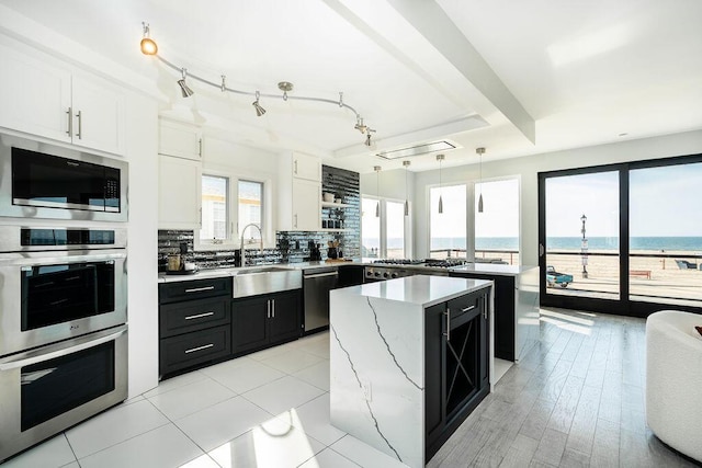 kitchen with appliances with stainless steel finishes, dark cabinetry, a center island, a peninsula, and backsplash