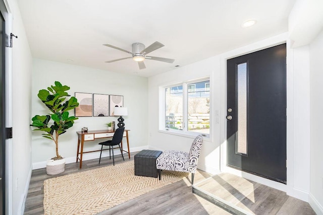 living area with baseboards, ceiling fan, and wood finished floors