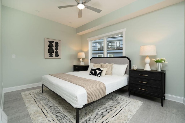 bedroom with baseboards, ceiling fan, and light wood-type flooring
