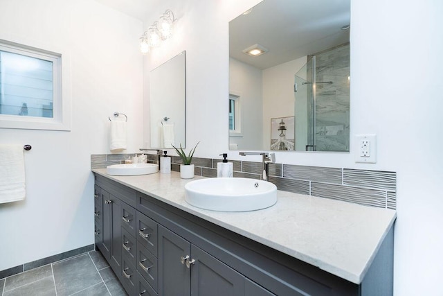 bathroom with double vanity, a sink, baseboards, and a stall shower